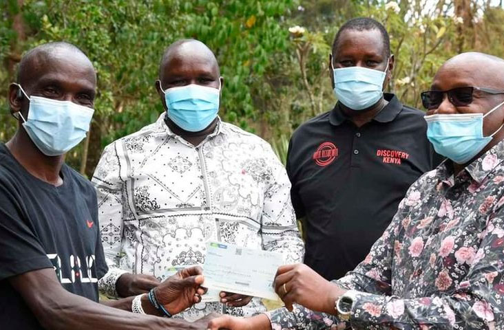 Kipchoge, junto con representantes del comité keniata luciendo el cheque / Jared Nyataya | Nation Media Group